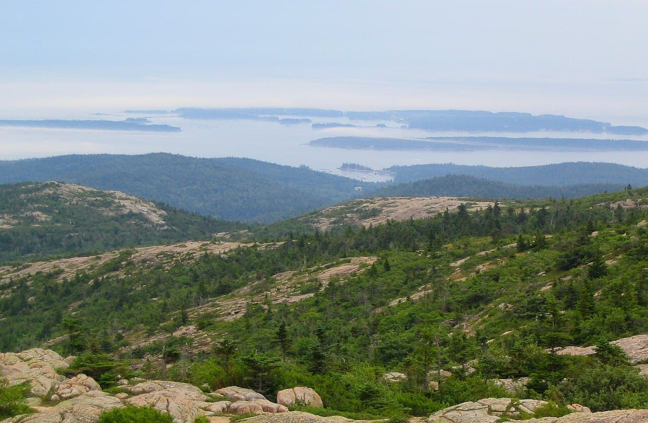 A high overlook across forested hills to a bay of scattered islands