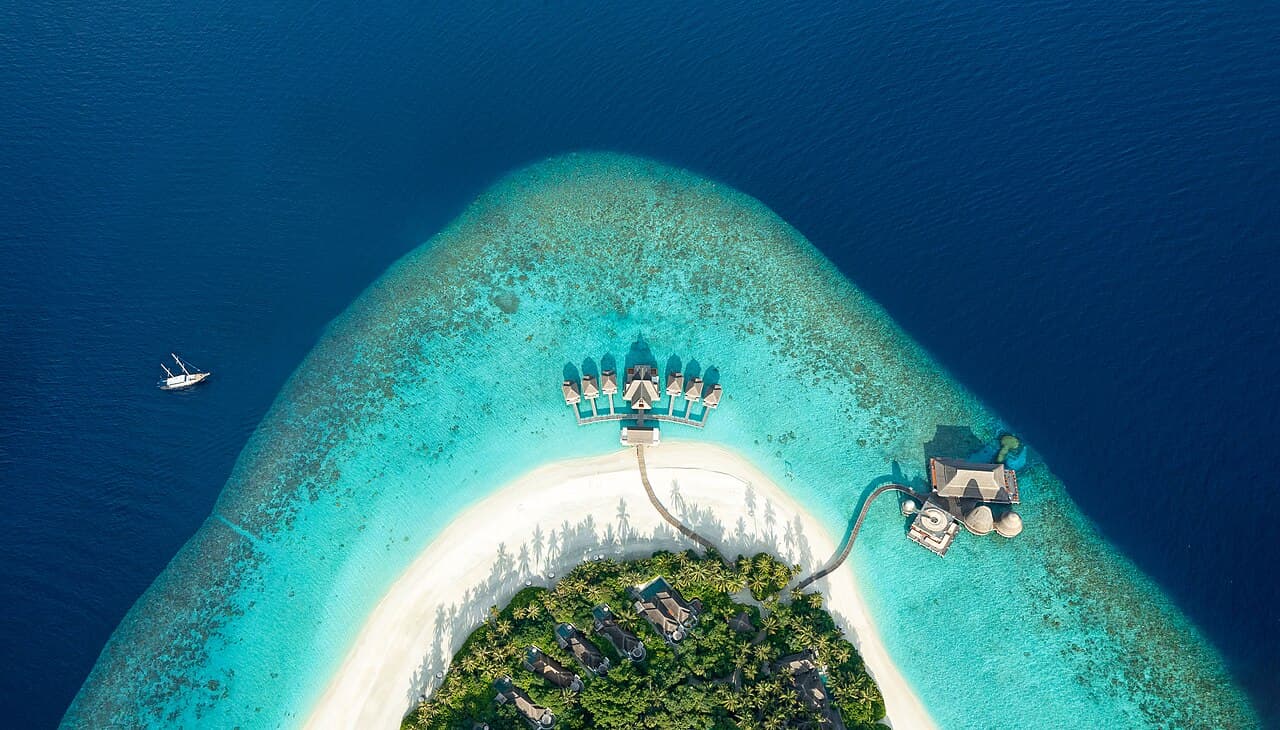 Aerial view of an over-water resort on a turquoise Maldivian atoll
